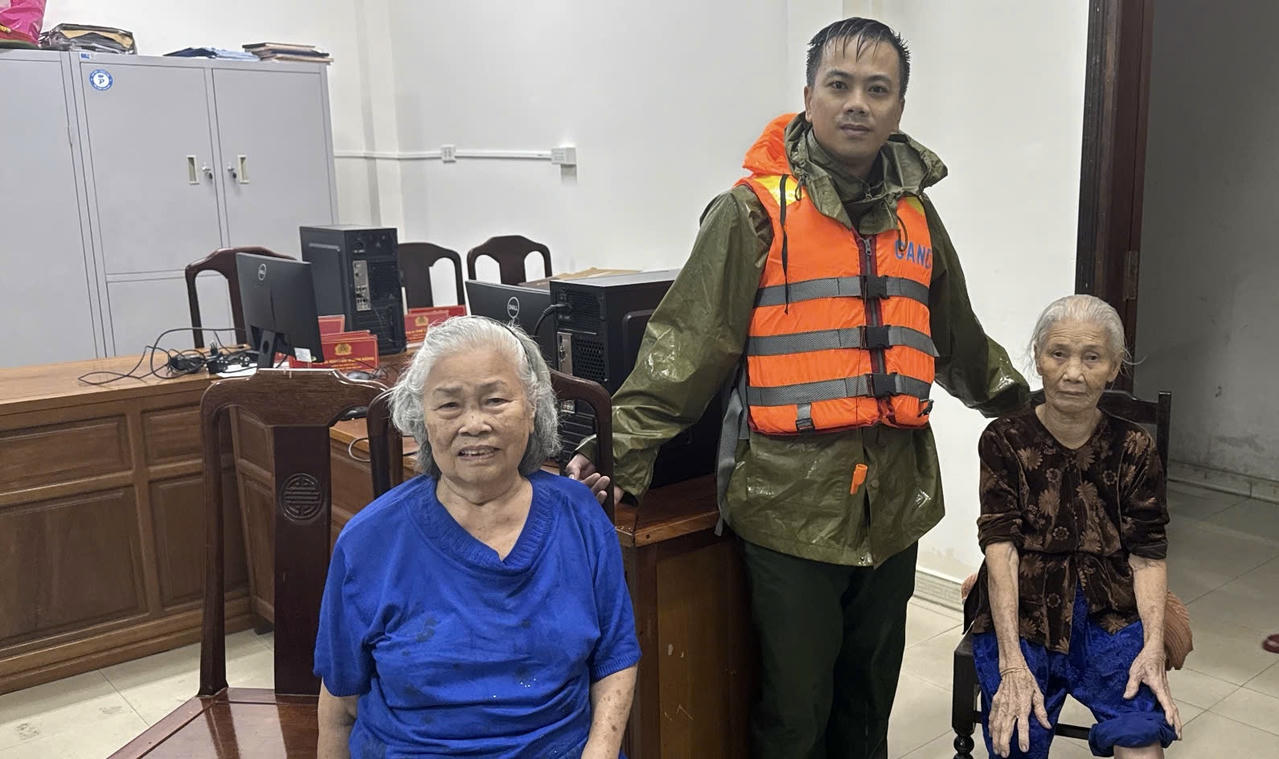 Đồng chí Hồ Vĩnh Cường, Công an phường An Cựu (TP Huế), cùng lực lượng hỗ trợ đưa hai cụ già từ khu vực ngập sâu về trụ sở Công an phường trú ẩn an toàn.