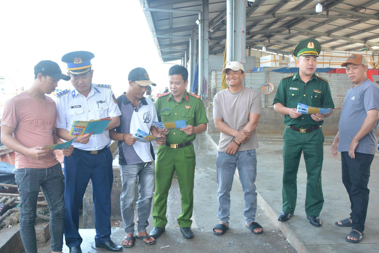 Các lực lượng tuyên truyền pháp luật đến ngư dân bằng tờ rơi.