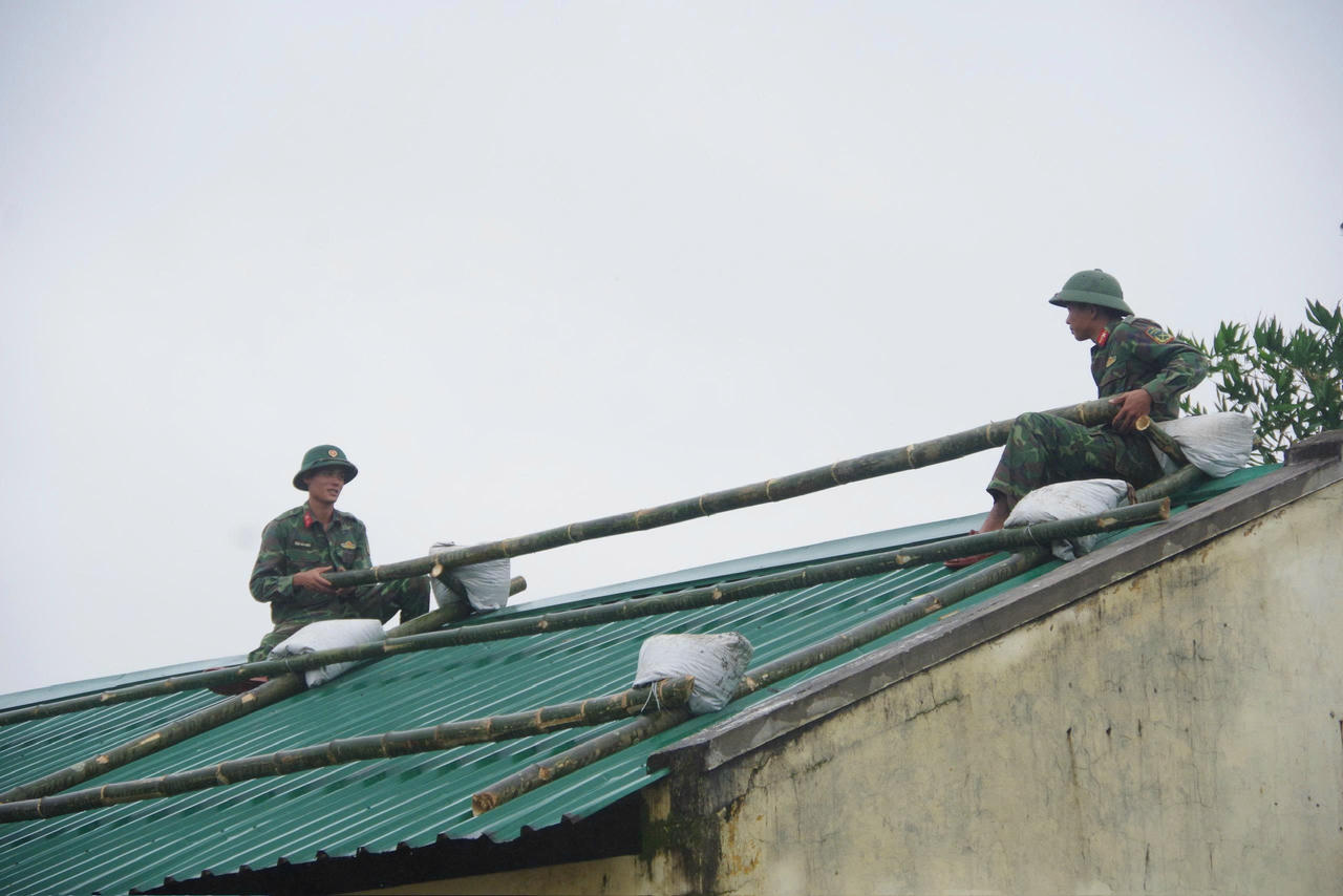 Lực lượng chức năng giúp dân chằng chống nhà cửa ứng phó với bão số 13.