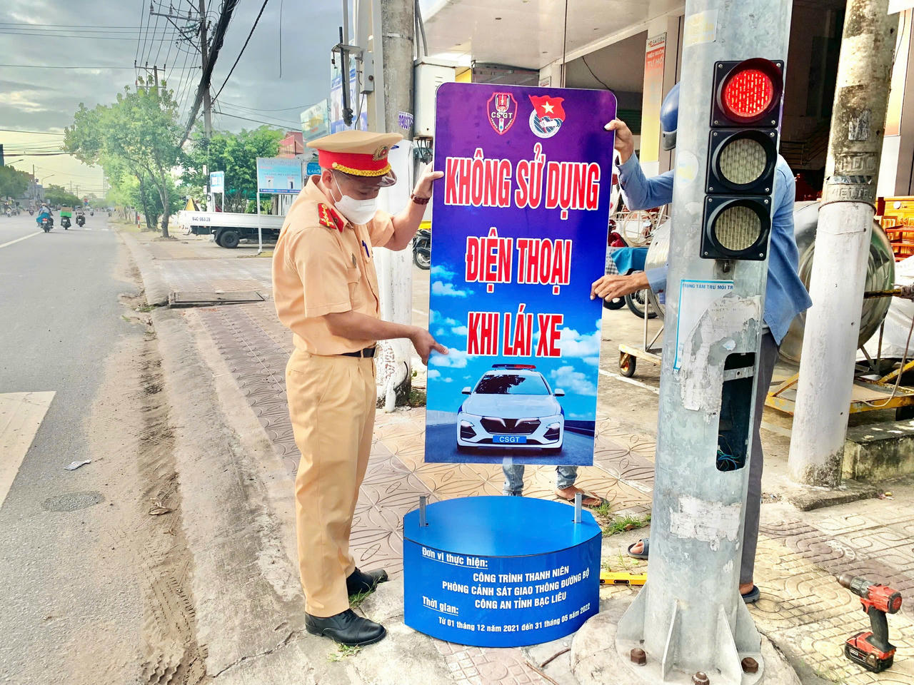 Đồng chí Trương Tấn Tài tham mưu lắp đặt pa nô tuyên truyền pháp luật về trật tự, an toàn giao thông.