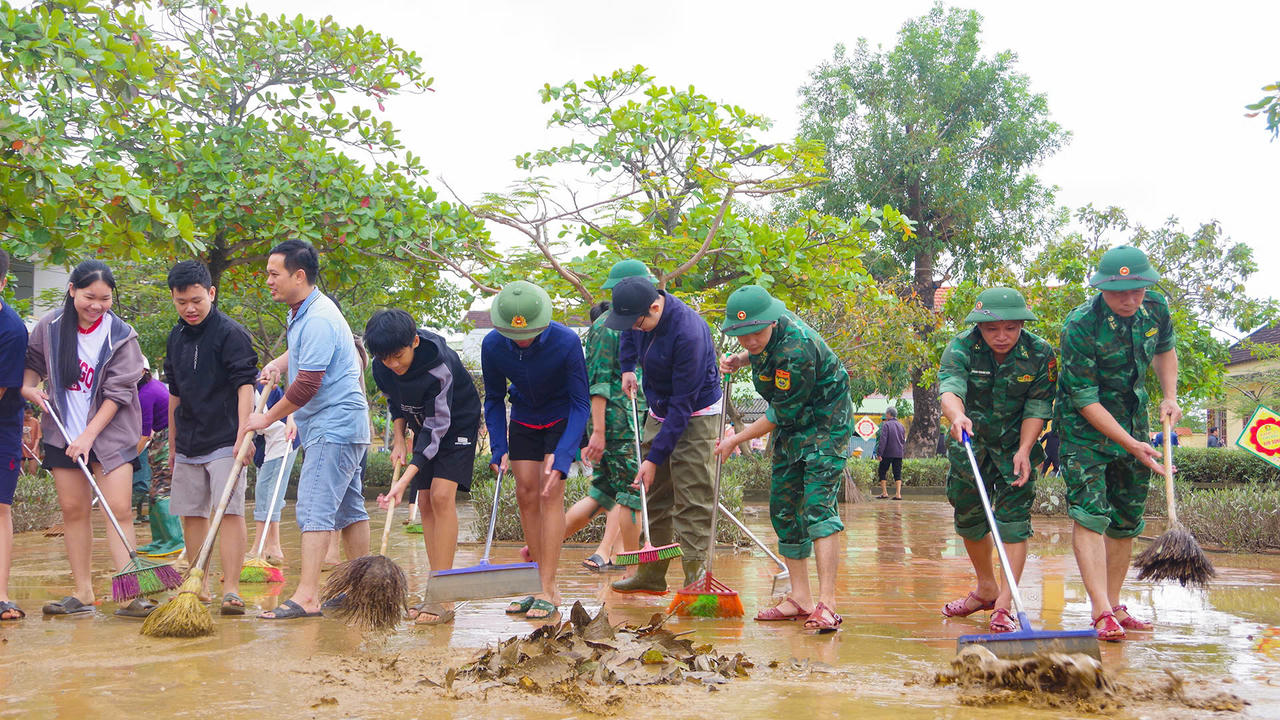 Cán bộ, chiến sĩ phối hợp cùng giáo viên, học sinh nhà trường dọn dẹp vệ sinh khắc phục hậu quả sau ngập lụt.