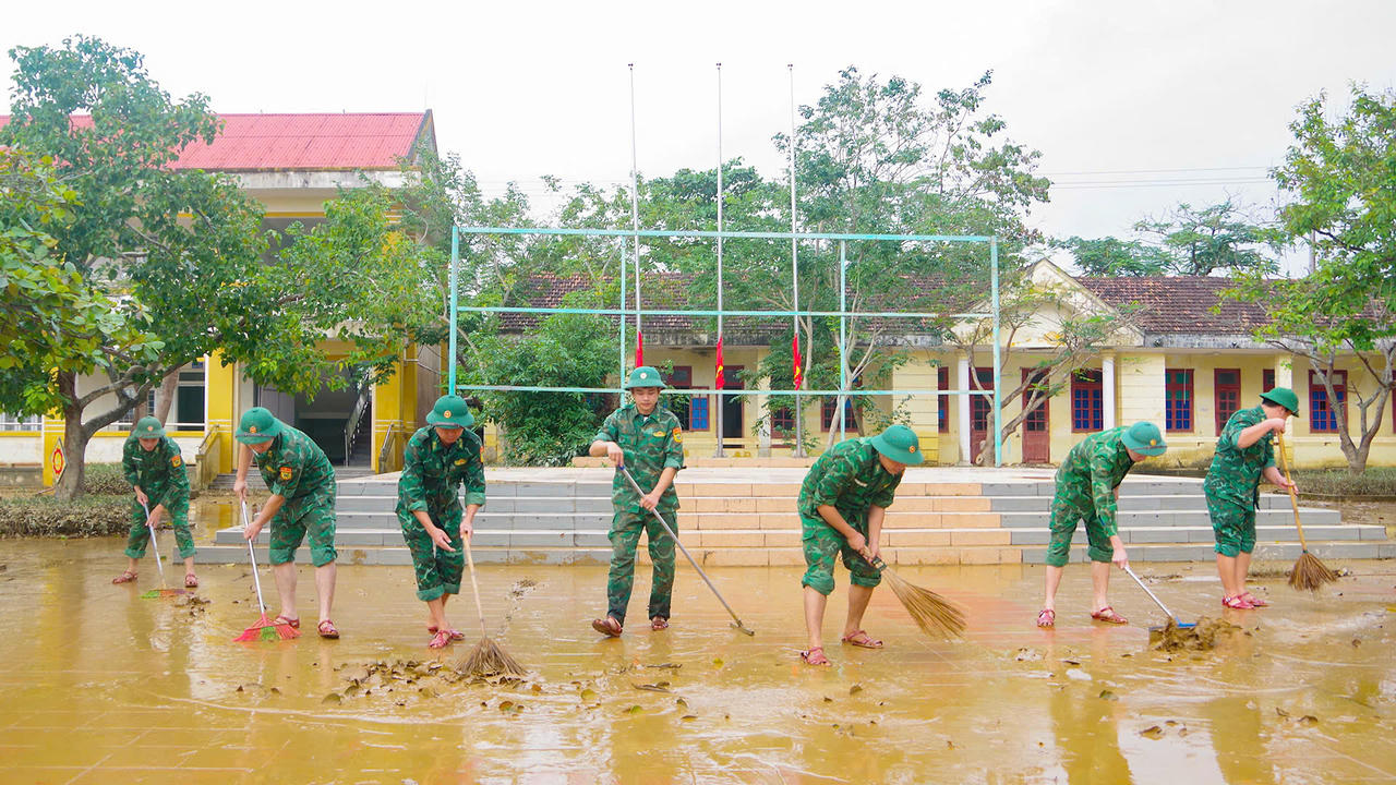 Cán bộ, chiến sĩ BĐBP tỉnh Quảng Trị lội bùn, thu dọn bùn đất, rác tại Trường THCS Kiến Giang ngay sau khi nước lũ rút.