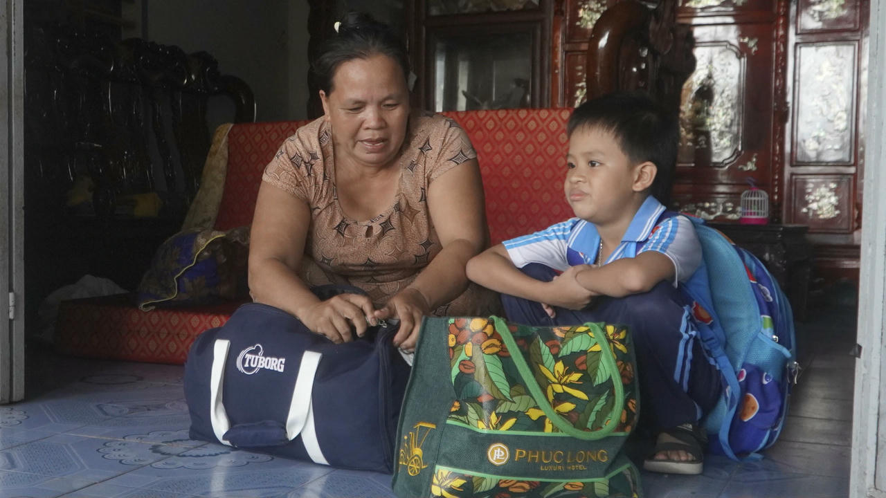 Bà Lê Thị Chút cùng cháu trai chuẩn bị đồ đạc để đi tránh trú bão.