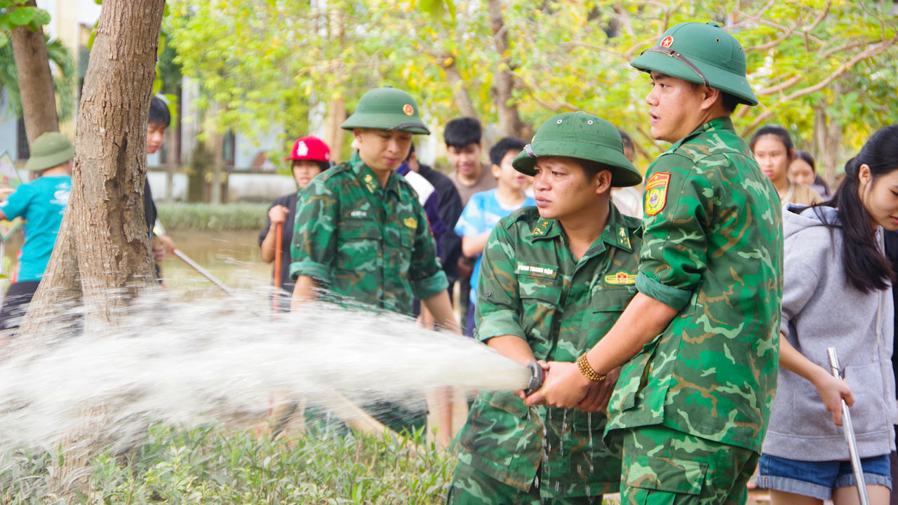 Cán bộ, chiến sĩ BĐBP tỉnh Quảng Trị phun nước rửa sạch bùn đất trong khuôn viên Trường THCS Kiến Giang.