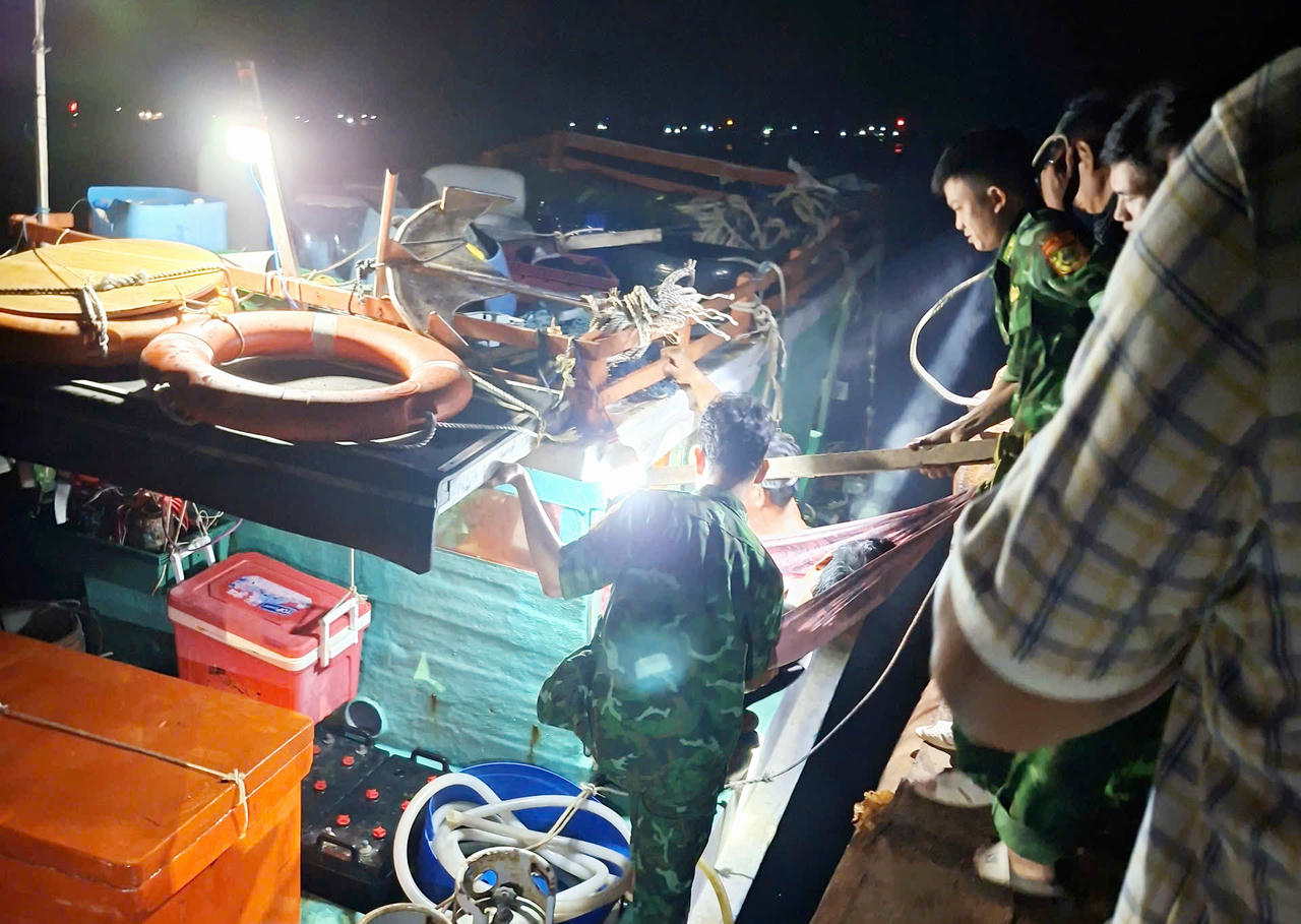 Cán bộ, chiến sĩ Đồn Biên phòng Hòn Chuối hỗ trợ đưa ông Đạt xuống tàu vào bờ cấp cứu, điều trị.
