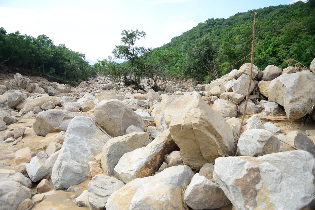 Đất đá do vụ vỡ đập hồ chứa nước vùi lập vườn sản xuất của người dân.