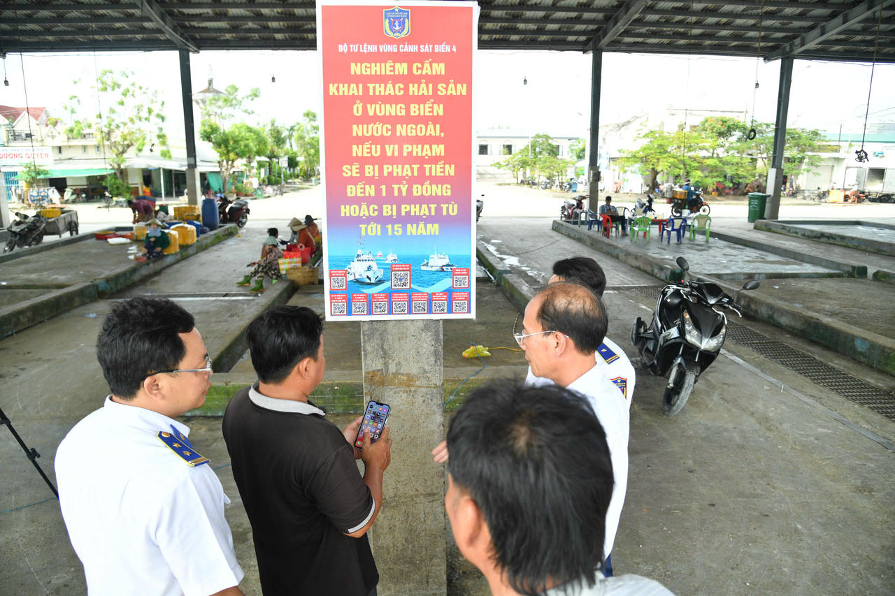Cán bộ BTL Vùng Cảnh sát biển 4 triển khai pano tuyên truyền tại cảng cá Sông Đốc và hướng dẫn cho bà con ngư dân quét mã QR tra cứu các quy định pháp luật về chống khai thác IUU.