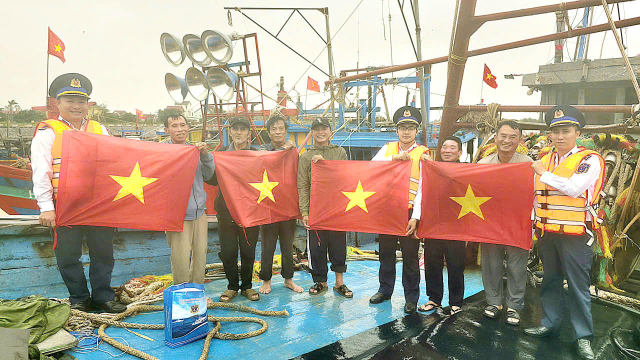 Cảnh sát biển phối hợp tuyên truyền IUU, tặng cờ Tổ quốc cho các tàu cá tại cảng cá Cửa Hội (Nghệ An).&nbsp;