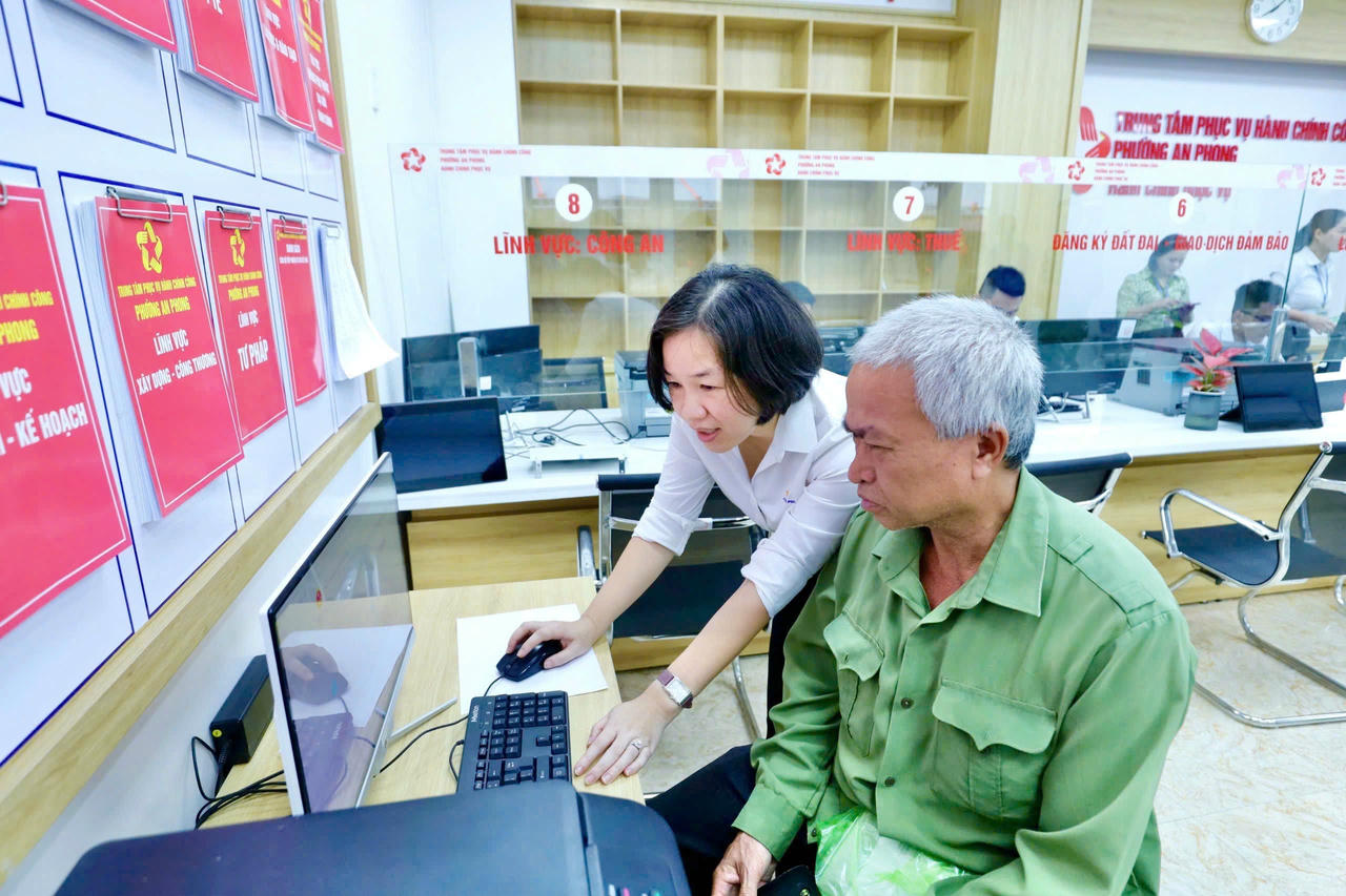 Cán bộ phường An Phong hướng dẫn người dân làm thủ tục trực tuyến.&nbsp;(Ảnh: Hải Anh)