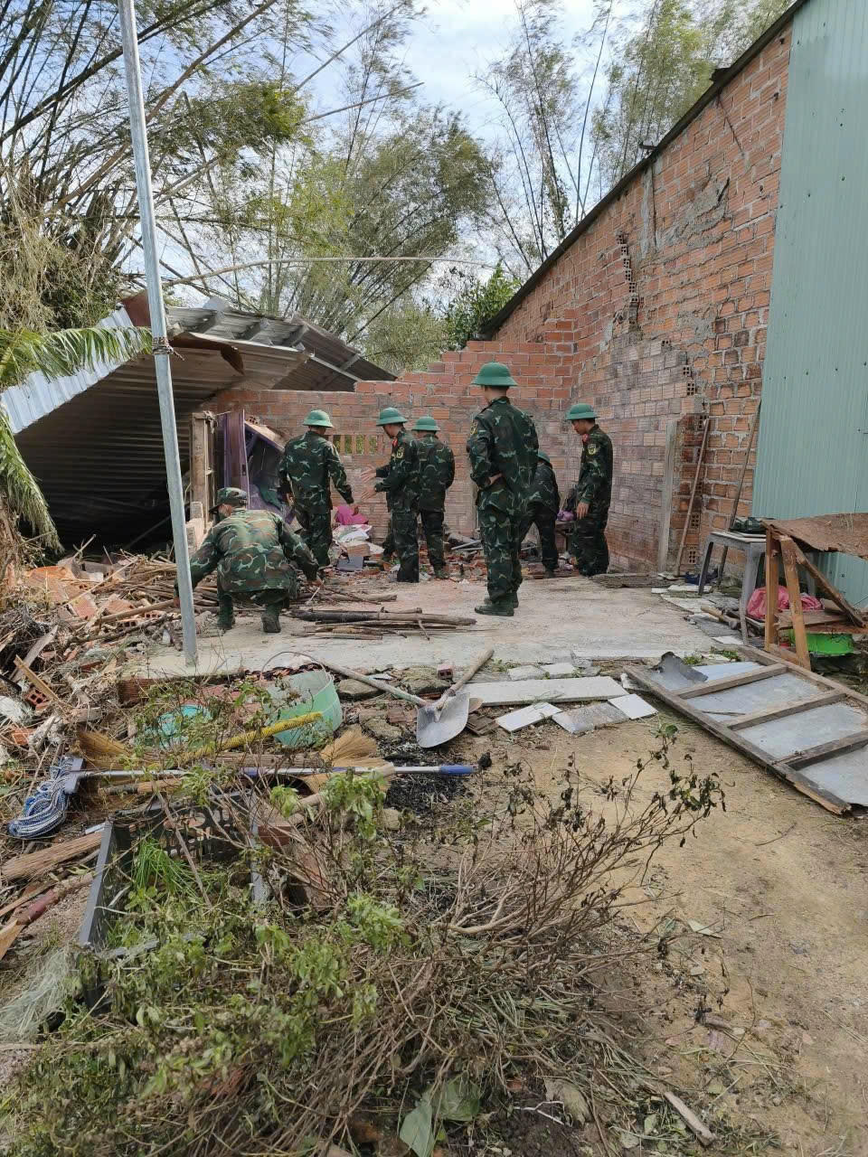 Lực lượng dân quân và Cảnh sát cơ động giúp người dân thu dọn, phân loại ngói vỡ để lợp lại mái nhà.