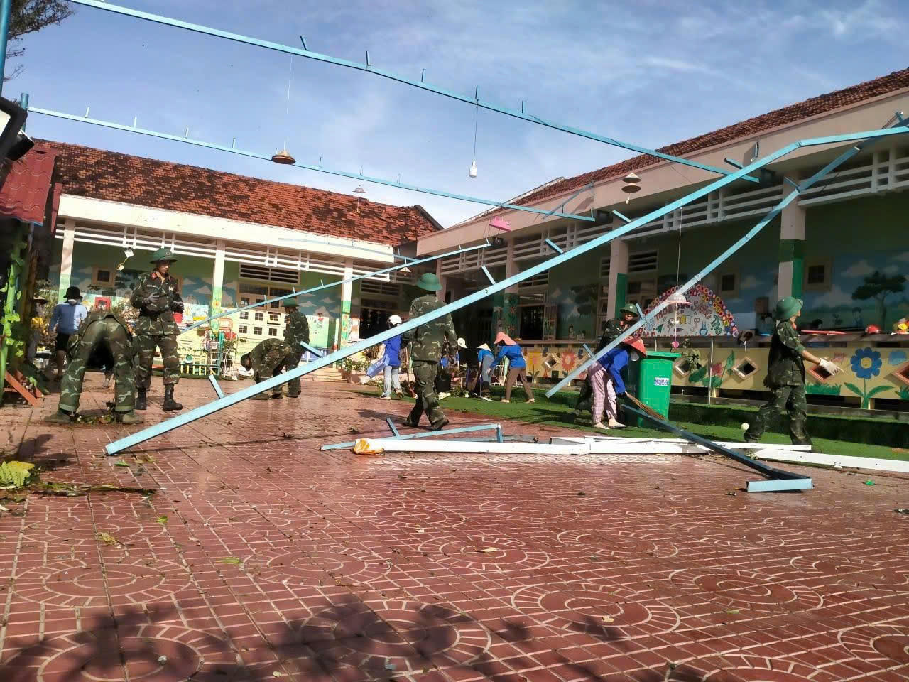 Các chiến sĩ cùng giáo viên dọn dẹp tại một điểm trường mầm non bị bão tàn phá nặng nề.