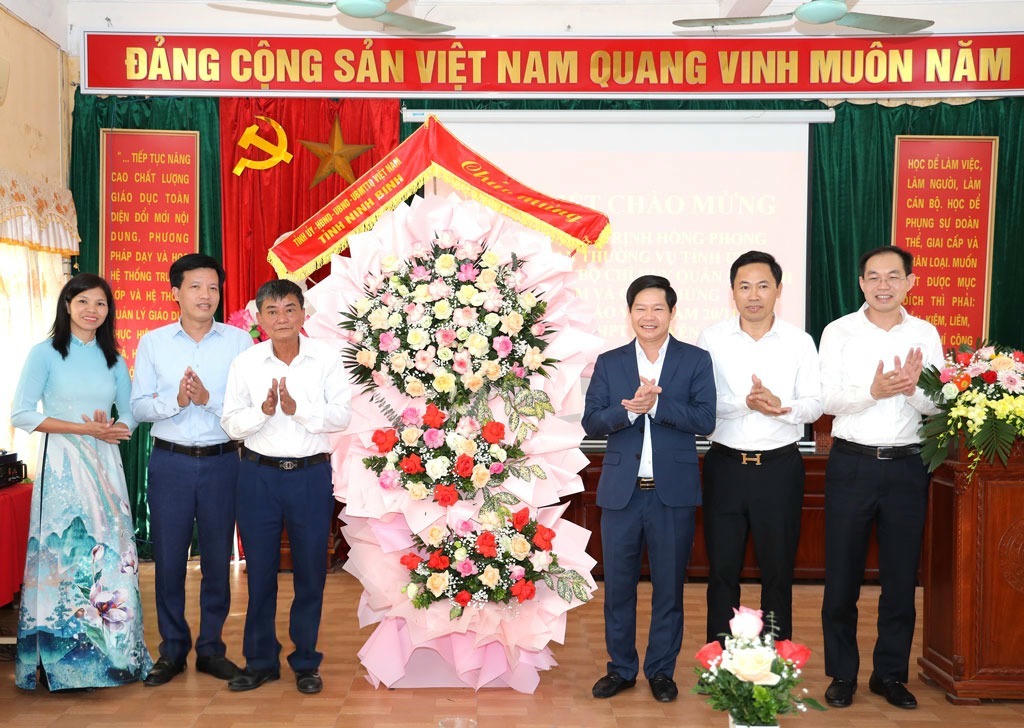 Đại tá Trịnh Hồng Phong - Chỉ huy trưởng Bộ Chỉ huy Quân sự tỉnh Ninh Bình tặng hoa chúc mừng tập thể cán bộ, giáo viên Trường THPT Nguyễn Trãi.