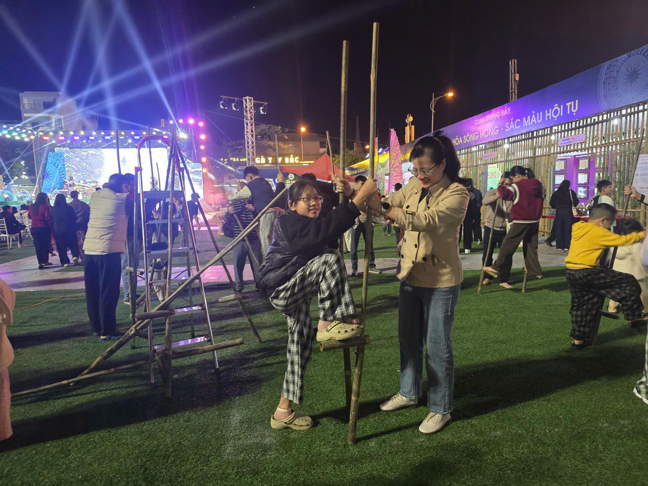 Người lớn và trẻ em cùng thử sức với trò chơi đi cà kheo truyền thống, hòa mình vào không khí sôi nổi, vui tươi của lễ hội văn hóa dân gian.