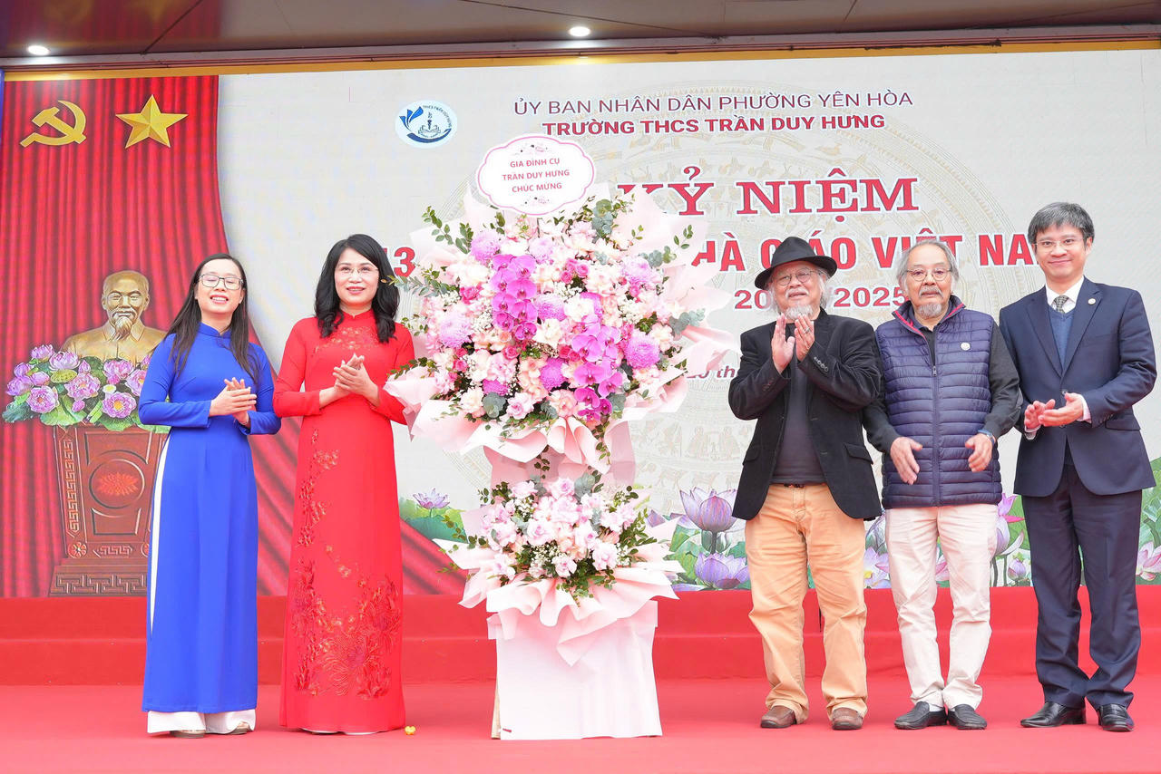 Đại diện gia đình cụ Trần Duy Hưng trao tặng lẵng hoa cho BGH nhà trường.