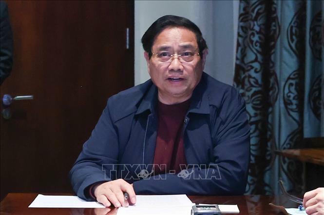 Thủ tướng Phạm Minh Chính chủ trì họp trực tuyến từ Nam Phi, chỉ đạo khắc phục hậu quả mưa lũ. Ảnh: Dương Giang/TTXVN