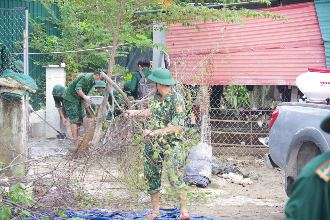 Cán bộ, chiến sĩ Bộ đội Biên phòng hỗ trợ người dân thu dọn sau mưa lũ.