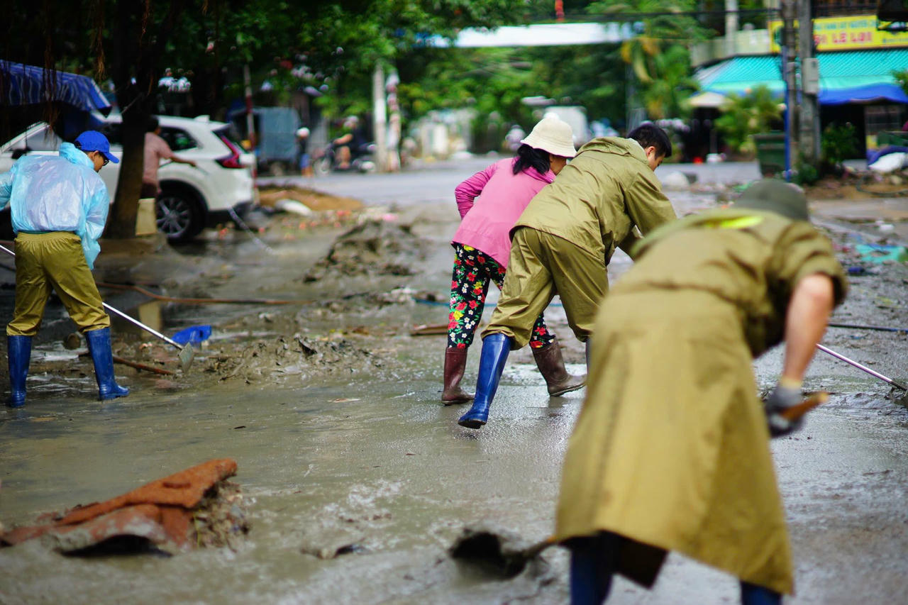 Lực lượng công an cùng người dân làm sạch môi trường sau khi nước lũ rút.