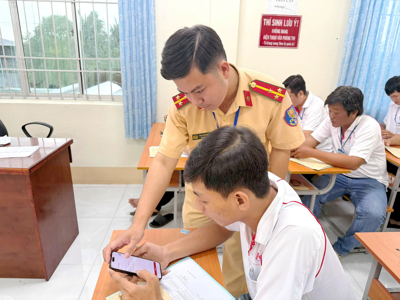Cán bộ Cảnh sát giao thông Cà Mau, hướng dẫn thí sinh cài đặt và sử dụng ứng dụng VNeTraffic trước khi tham gia kỳ sát hạch.