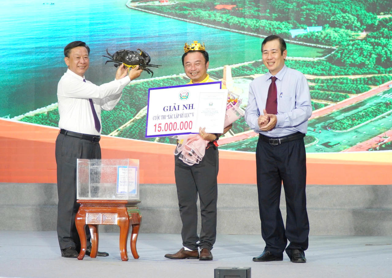 Ông Hồ Trung Việt - Ủy viên Ban Thường vụ Tỉnh ủy, Trưởng Ban Tuyên giáo và Dân vận Tỉnh ủy Cà Mau (bên trái) trao chứng nhận cho đại diện Công ty TNHH Dư Thái Bình, có con cua nặng 1,820 kg, đạt giải Nhất cuộc thi cua có trọng lượng lớn nhất.