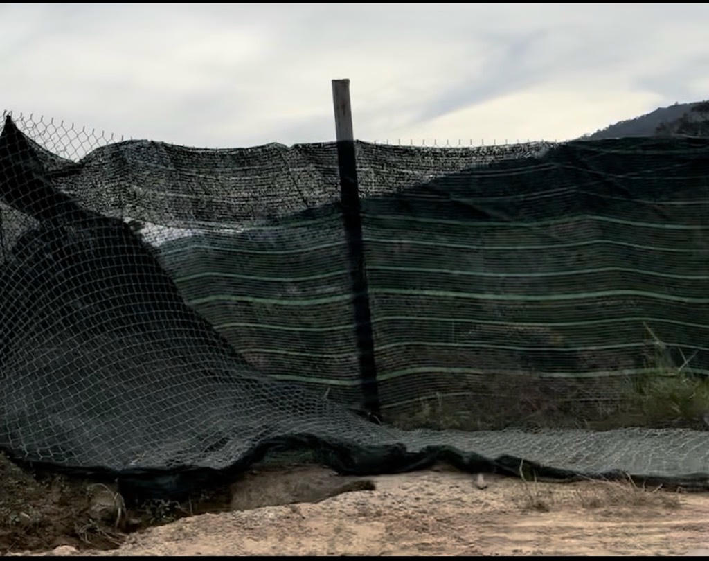 Dãy lưới đen che đoạn suối diễn ra hoạt động khai thác cát trái phép.