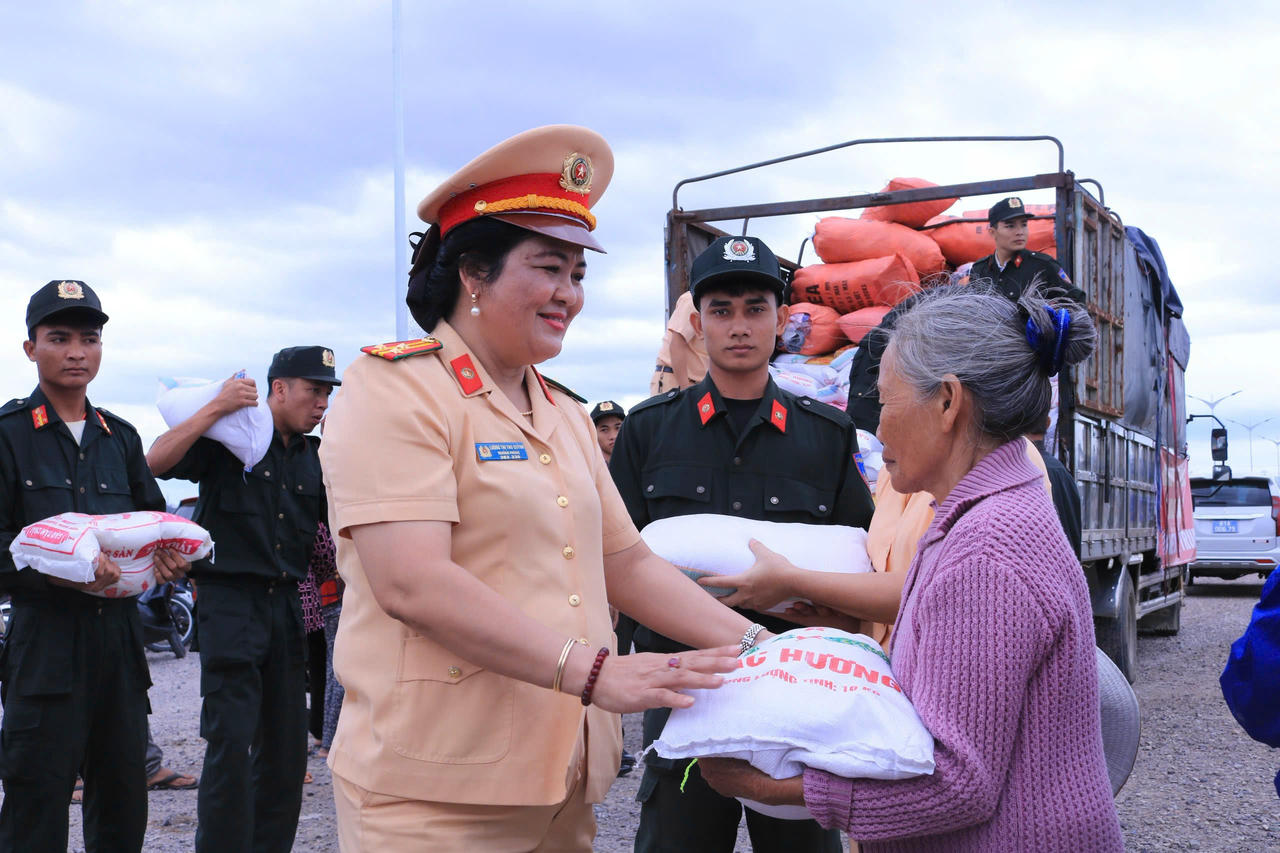 Thượng tá Lương Thị Thu Quỳnh, Trưởng phòng PC08 thăm hỏi, động viên bà con khi tiếp nhận nhu yếu phẩm cứu trợ.