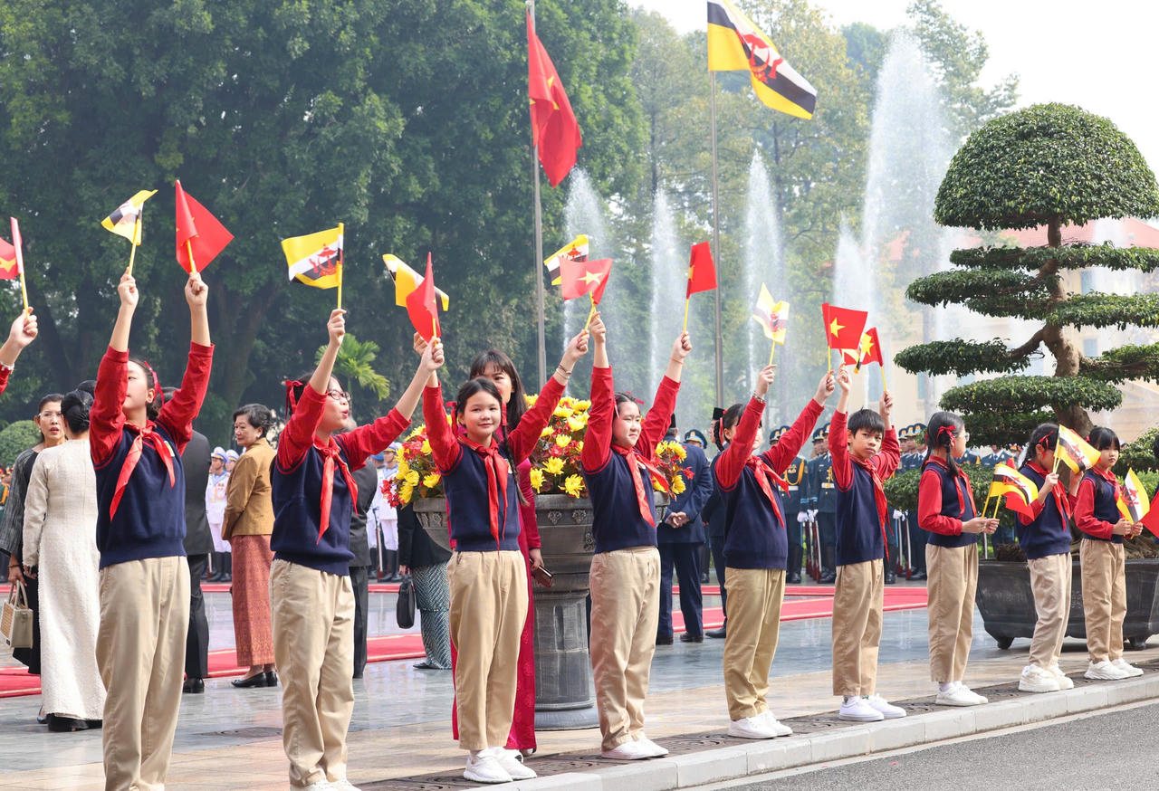 Đông đảo các cháu thiếu nhi Thủ đô có mặt tại Phủ Chủ tịch vẫy cờ hai nước chào đón Quốc vương Haji Hassanal Bolkiah cùng Đoàn cấp cao Brunei. Ảnh: VGP