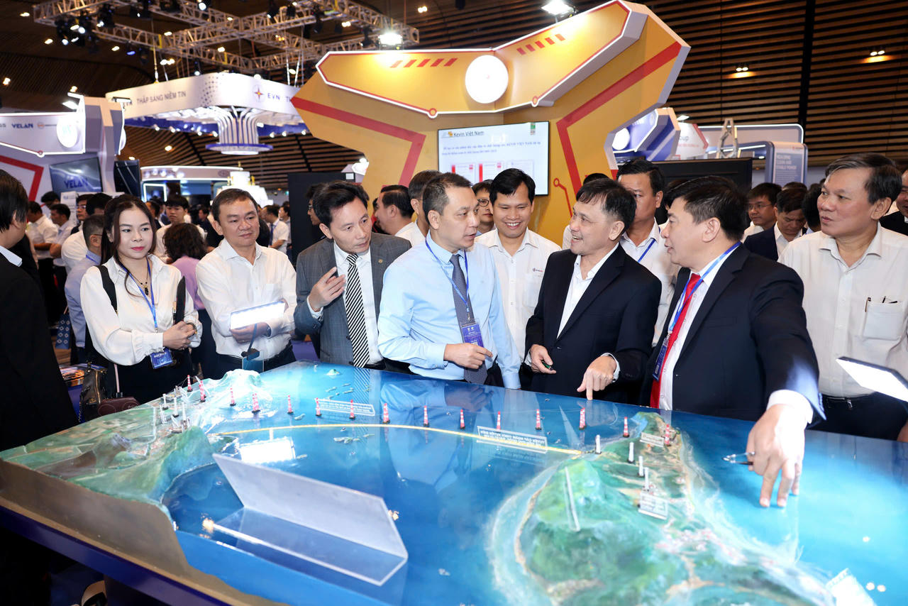 Chủ tịch HĐTV EVN Đặng Hoàng An (áo xanh), ông Mai Quốc Hội - Phó Chủ tịch kiêm Tổng thư ký Hội Điện lực Việt Nam (áo xám) cùng các đại biểu tham quan gian hàng EVNSPC.