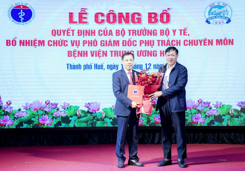 Thứ trưởng Bộ Y tế Đỗ Xuân Tuyên (bên phải) trao quyết định và tặng hoa chúc mừng TS.BS. Hồ Văn Linh.