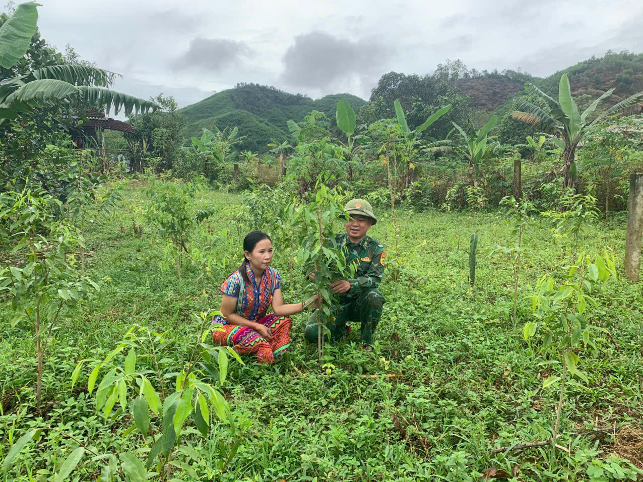 Thiếu tá Đoàn Văn Tiệp hướng dẫn, giúp đỡ chị Hồ Thị Khiên chăm sóc cây gió trầm.
