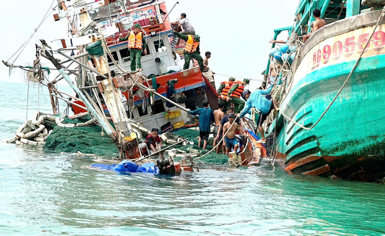 Cán bộ, chiến sĩ Đồn Biên phòng Hòn Chuối và ngư dân hỗ trợ đưa người và tài sản từ tàu cá bị chìm lên tàu cứu nạn.