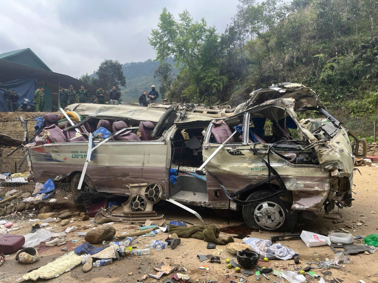 Chiếc xe ô tô bị hư hỏng nặng, thân xe bẹp rúm, kính vỡ, nhiều vật dụng văng ra xung quanh.