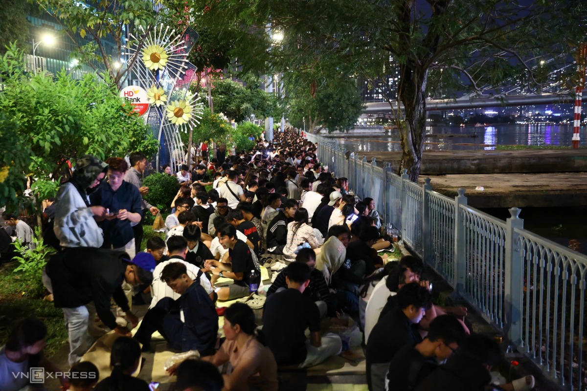 Người dân ngồi giữ chỗ ven sông Sài Gòn chờ xem pháo hoa. Ảnh: Quỳnh Trần - VNExpress
