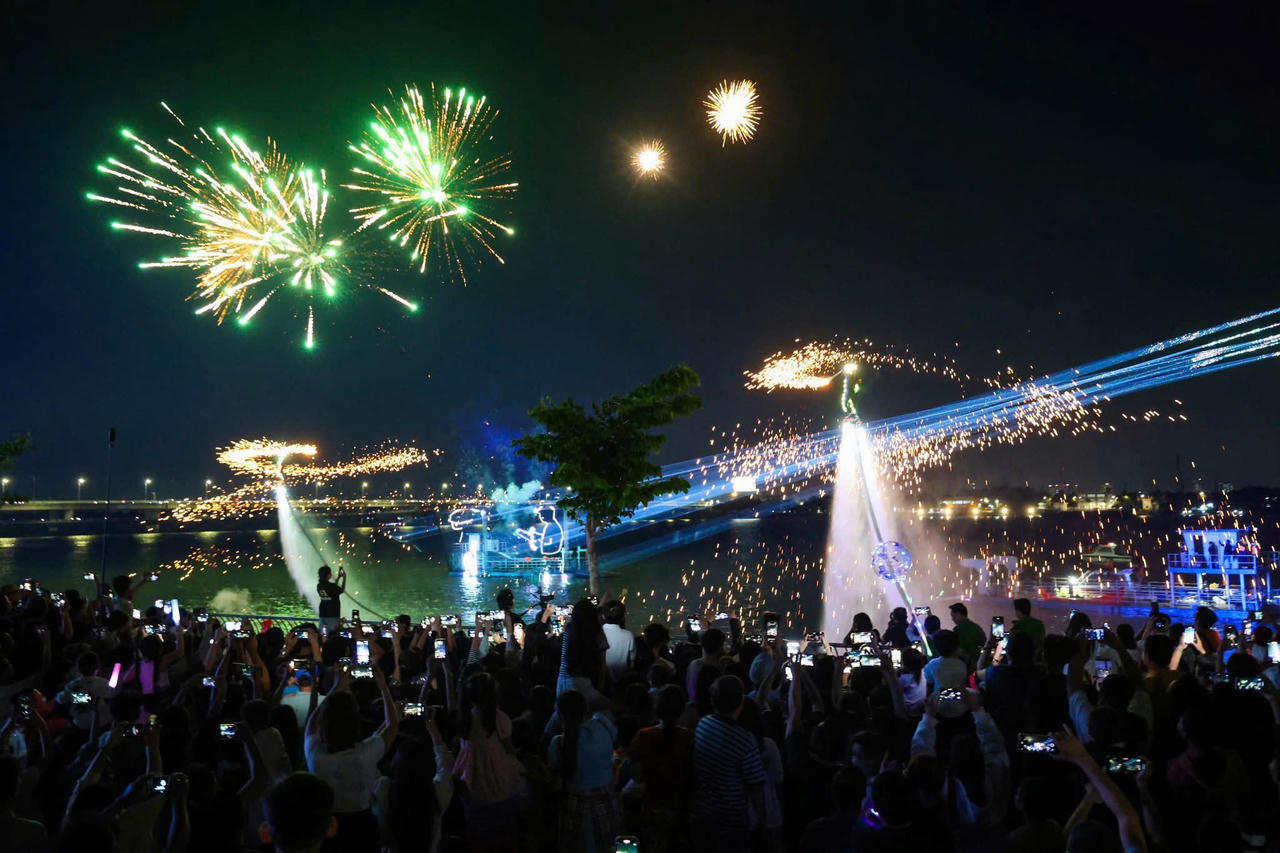 Các vận động viên flyboard biểu diễn trên sông Đồng Nai trong màn trình diễn kết hợp pháo hoa và ánh sáng rực rỡ.