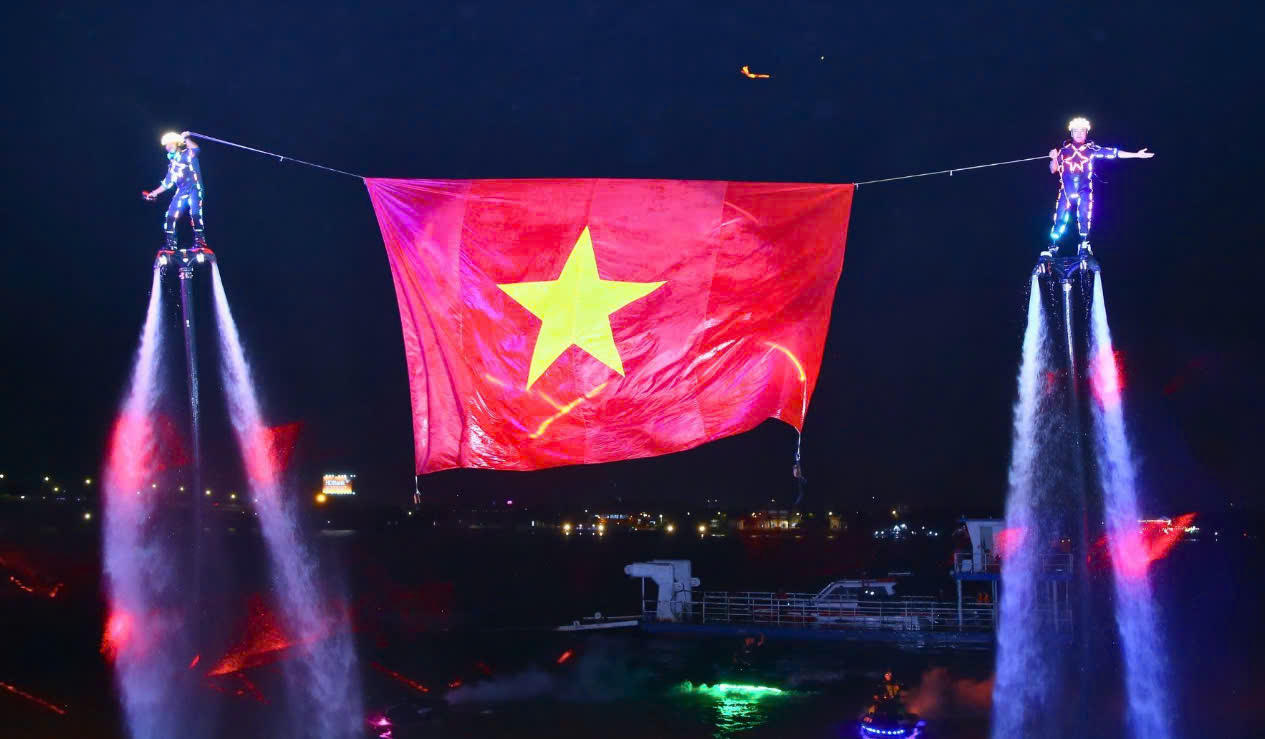 Khoảnh khắc ấn tượng khi các vận động viên flyboard phối hợp nâng lá cờ Việt Nam giữa dòng sông.