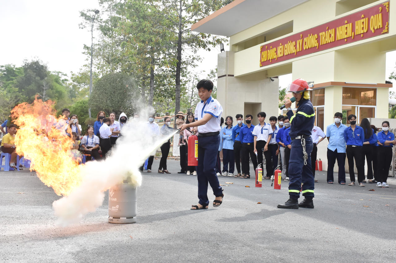 Cán bộ, chiến sĩ Công an tỉnh hướng dẫn học sinh sử dụng bình chữa cháy xách tay để dập lửa.