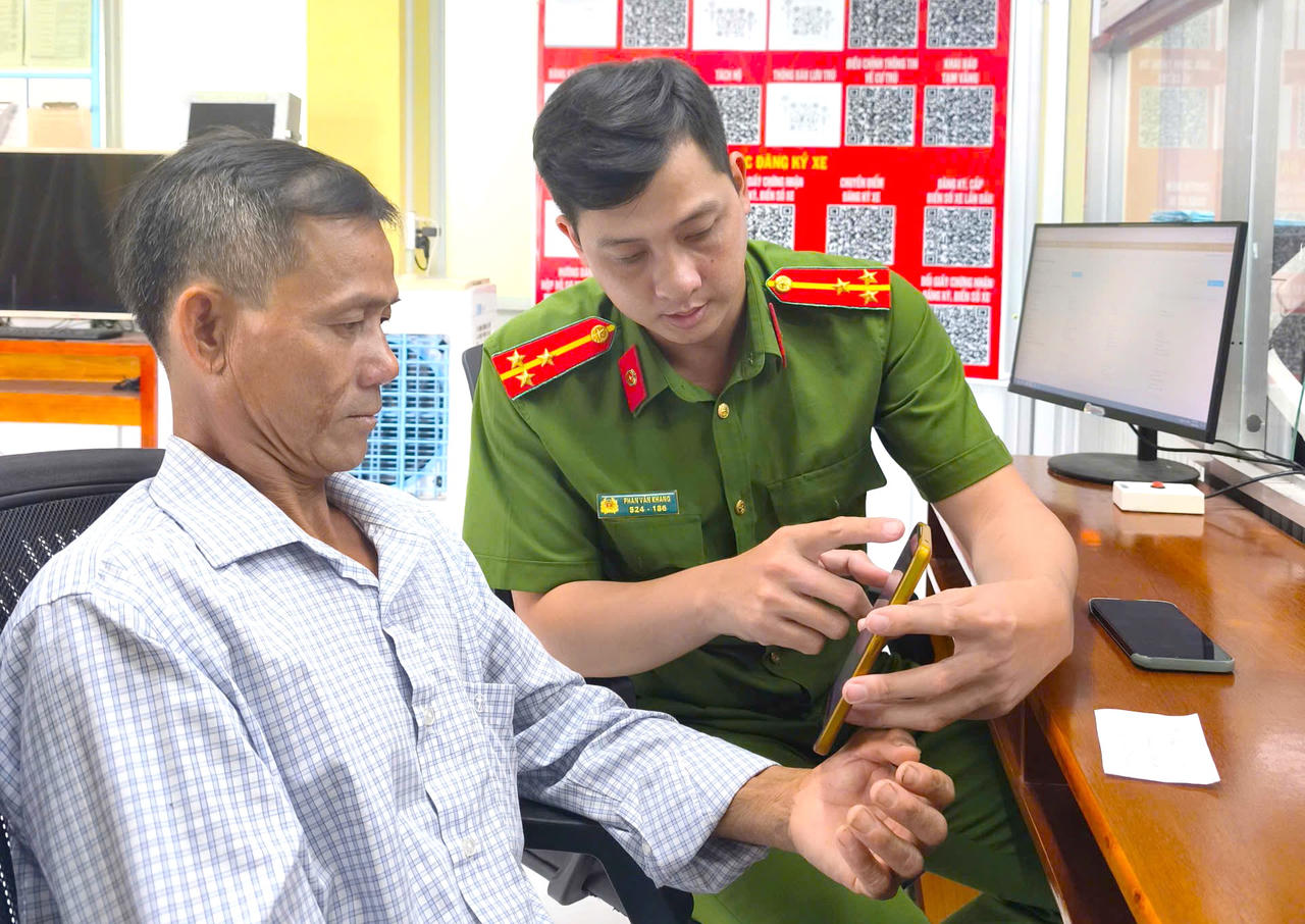 Cán bộ Công an xã hướng dẫn người dân kiểm tra thông tin “phạt nguội” trên ứng dụng VNeTraffic.