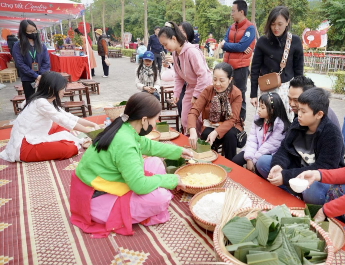 Cư dân cùng các em nhỏ hào hứng trải nghiệm gói bánh chưng tại Chợ Tết Ciputra 2026, lưu giữ nét đẹp truyền thống giữa không gian đô thị hiện đại.