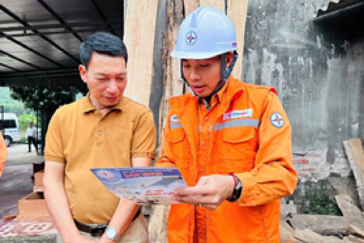 Anh Khổng Minh Thắng (bên phải) hướng dẫn người dân sử dụng điện an toàn dịp Tết.