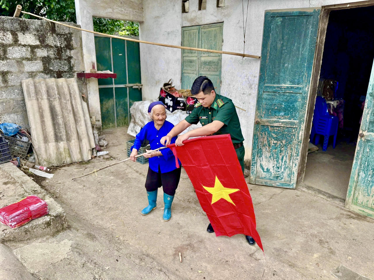 Cán bộ Đồn Biên phòng Đàm Thuỷ giúp người dân treo cờ Tổ Quốc. (Ảnh: Đồn BP Đàm Thuỷ)