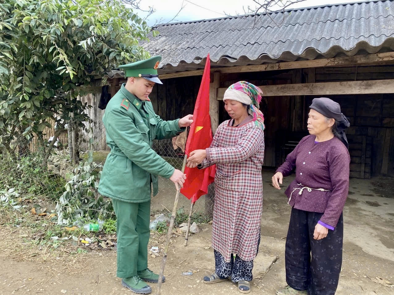 Chiến sĩ Đồn Biên phòng Xuân Trường giúp người dân treo cờ Tổ quốc. (Ảnh: Lê Hanh)