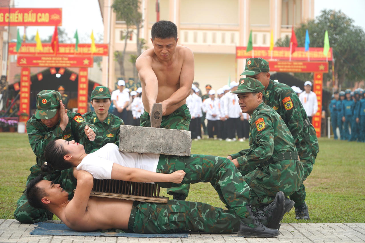 Các chiến sĩ nằm trên mảnh chai và bàn chông, trên bụng đặt tấm bê tông nặng 70kg. Ảnh: Tuyết Lan