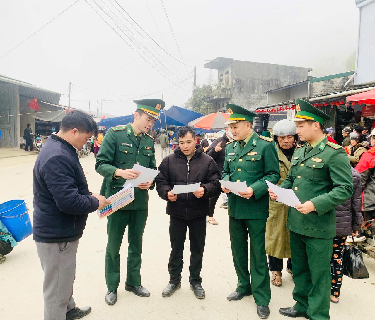 Cán bộ, chiến sĩ Đồn Biên phòng Nghĩa Thuận, Bộ đội Biên phòng tỉnh Tuyên Quang phát tờ rơi về bầu cử đến người dân tại chợ biên mậu mốc 325 xã Nghĩa Thuận. (Ảnh: Hoàng Chính)