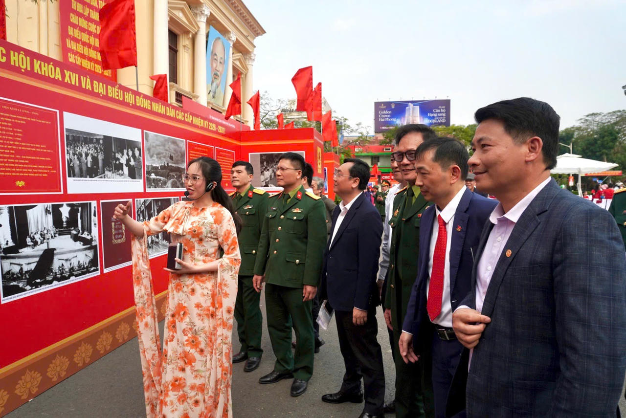 Các đại biểu tham quan triển lãm và nghe giới thiệu về ảnh, tư liệu.