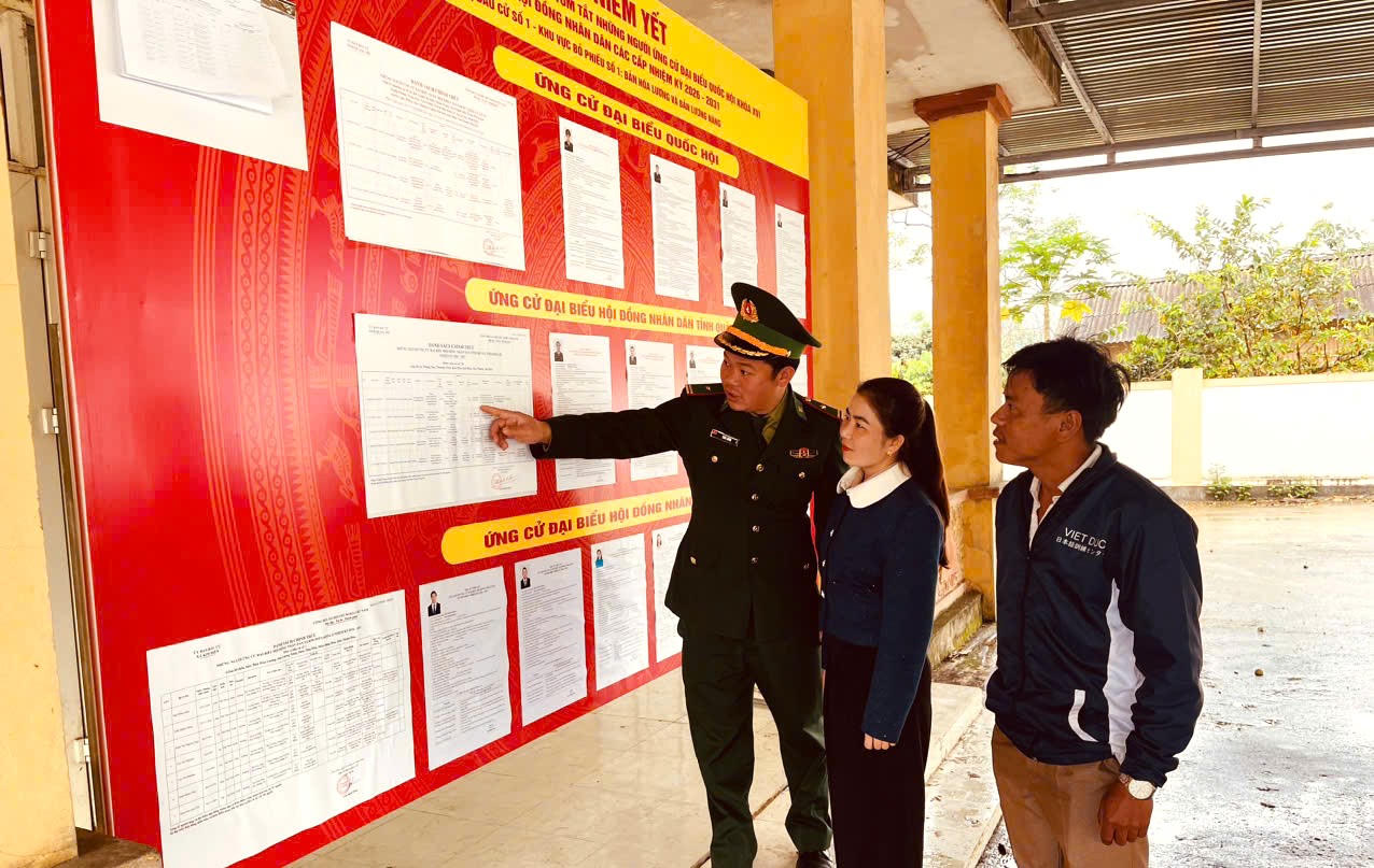 Trưởng bản Cao Trưởng Thành cùng cán bộ Biên phòng tìm hiểu danh sách, tiểu sử các ứng cử viên được niêm yết tại khu vực bầu cử.