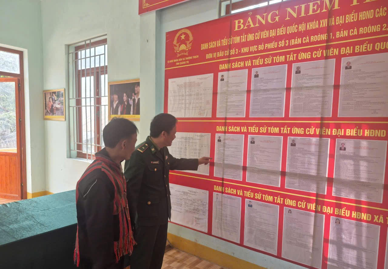 Phó Chủ tịch Thường trực Ủy ban MTTQ Việt Nam xã Cà Roòng 1 Đinh Hậu cùng cán bộ Biên phòng tìm hiểu danh sách, tiểu sử tóm tắt các ứng cử viên được niêm yết tại khu vực bầu cử.