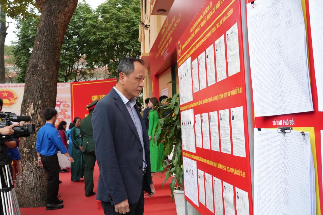 Trước khi thực hiện bỏ phiếu, ông Lê Hồng Hà xem danh sách cử tri và tìm hiểu thông tin các ứng cử viên được niêm yết tại khu vực bầu cử.