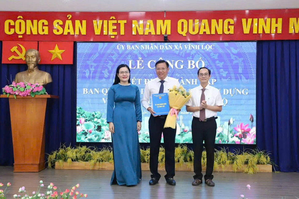 Ông Huỳnh Cao Cường - Bí thư Đảng ủy, Chủ tịch HĐND xã (bìa phải) và bà Nguyễn Thị Thảo - Phó Bí thư Đảng ủy, Chủ tịch UBND xã Vĩnh Lộc trao quyết định bổ nhiệm chức vụ Giám đốc Ban cho ông Nguyễn Hữu Trí.