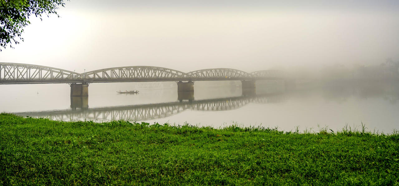 Trong làn sương mỏng buổi sớm, cầu Trường Tiền hiện lên mềm mại như một dải lụa, ôm trọn dòng Hương Giang yên bình.