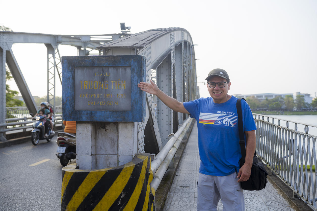 Du khách nước ngoài thích thú chụp ảnh bên tấm bảng giới thiệu cầu Trường Tiền, lưu lại khoảnh khắc đáng nhớ bên sông Hương thơ mộng.