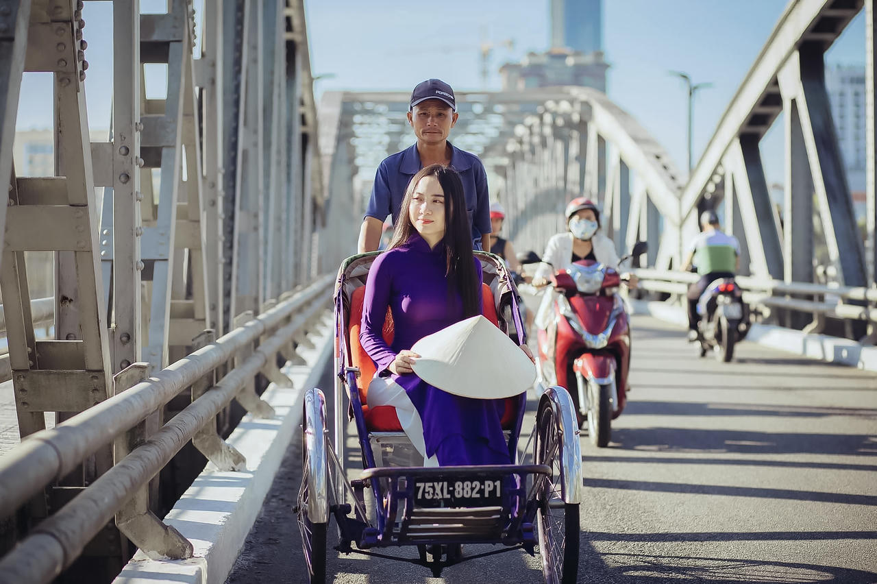 Tà áo dài tím, chiếc nón bài thơ trên tay cô gái theo nhịp xích lô chầm chậm qua cầu Trường Tiền, gợi lên vẻ dịu dàng rất riêng của Huế.